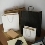 Arranged shopping bags and laptop on a wooden table, representing online shopping.