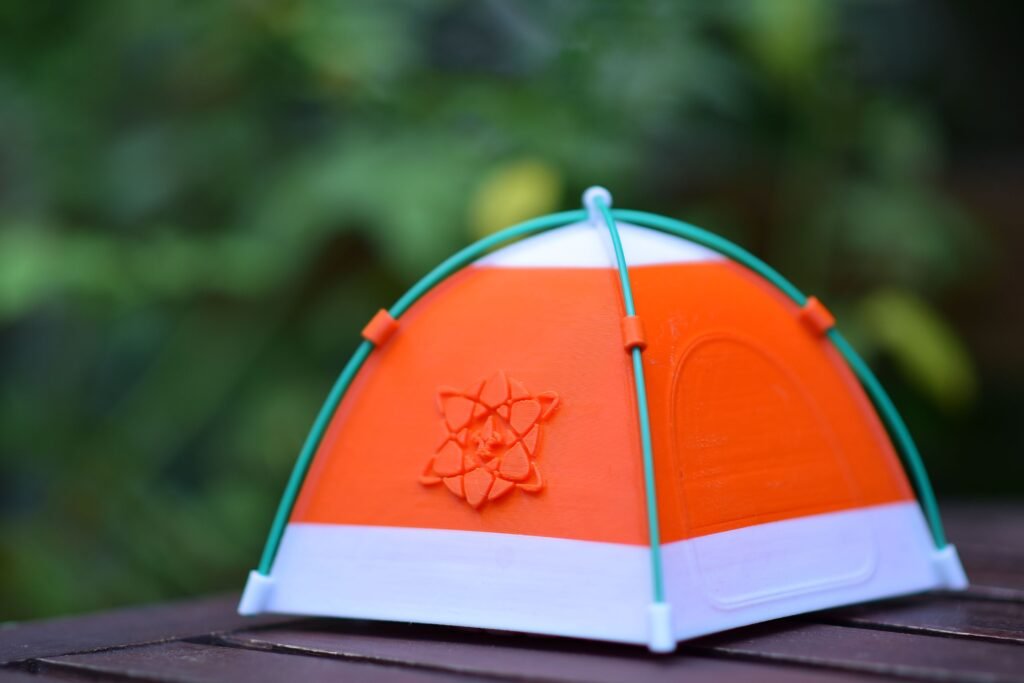 Colorful miniature orange tent with atomic symbol on wooden surface, ideal for creative and educational themes.