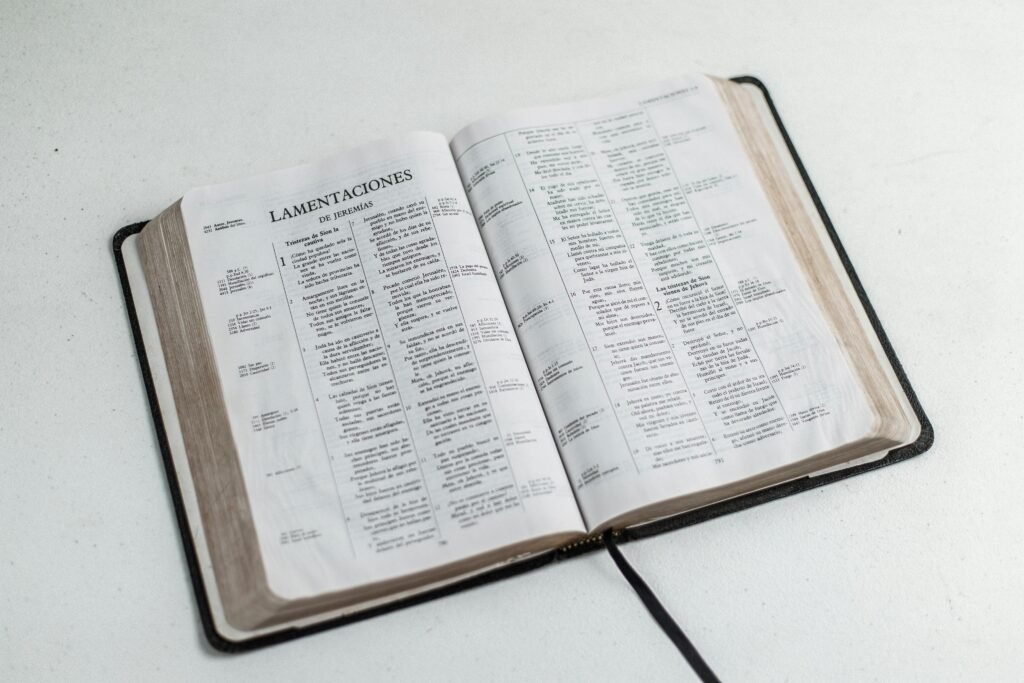 An open Bible displaying Lamentations, placed on a white surface.